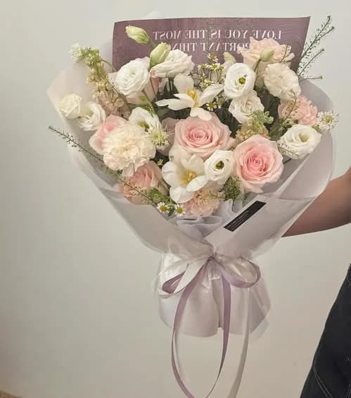 An ivory and sage bouquet on a pale surface